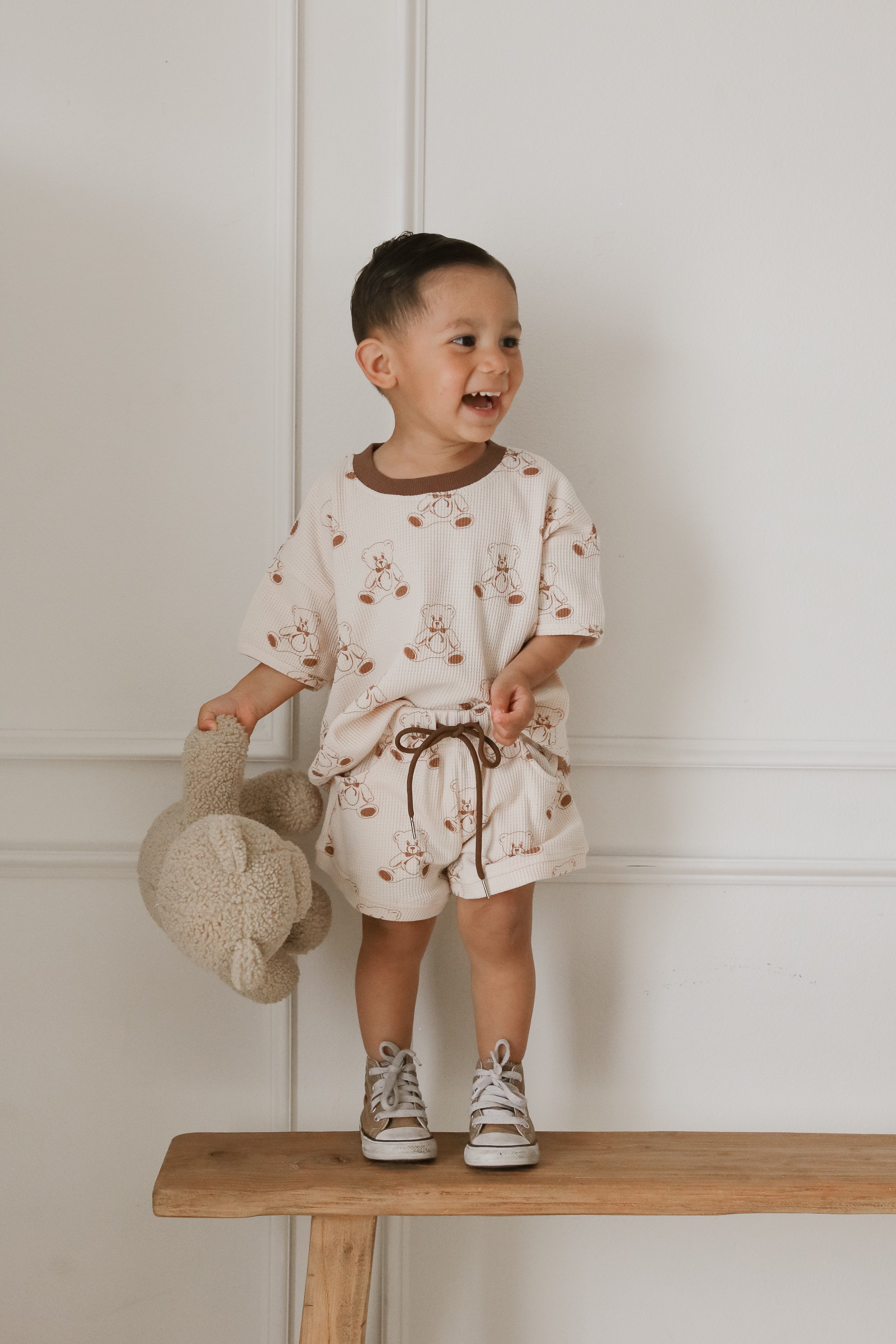 Smiling child wearing a printed waffle set with teddy bear, perfect for summer days and playful adventures.