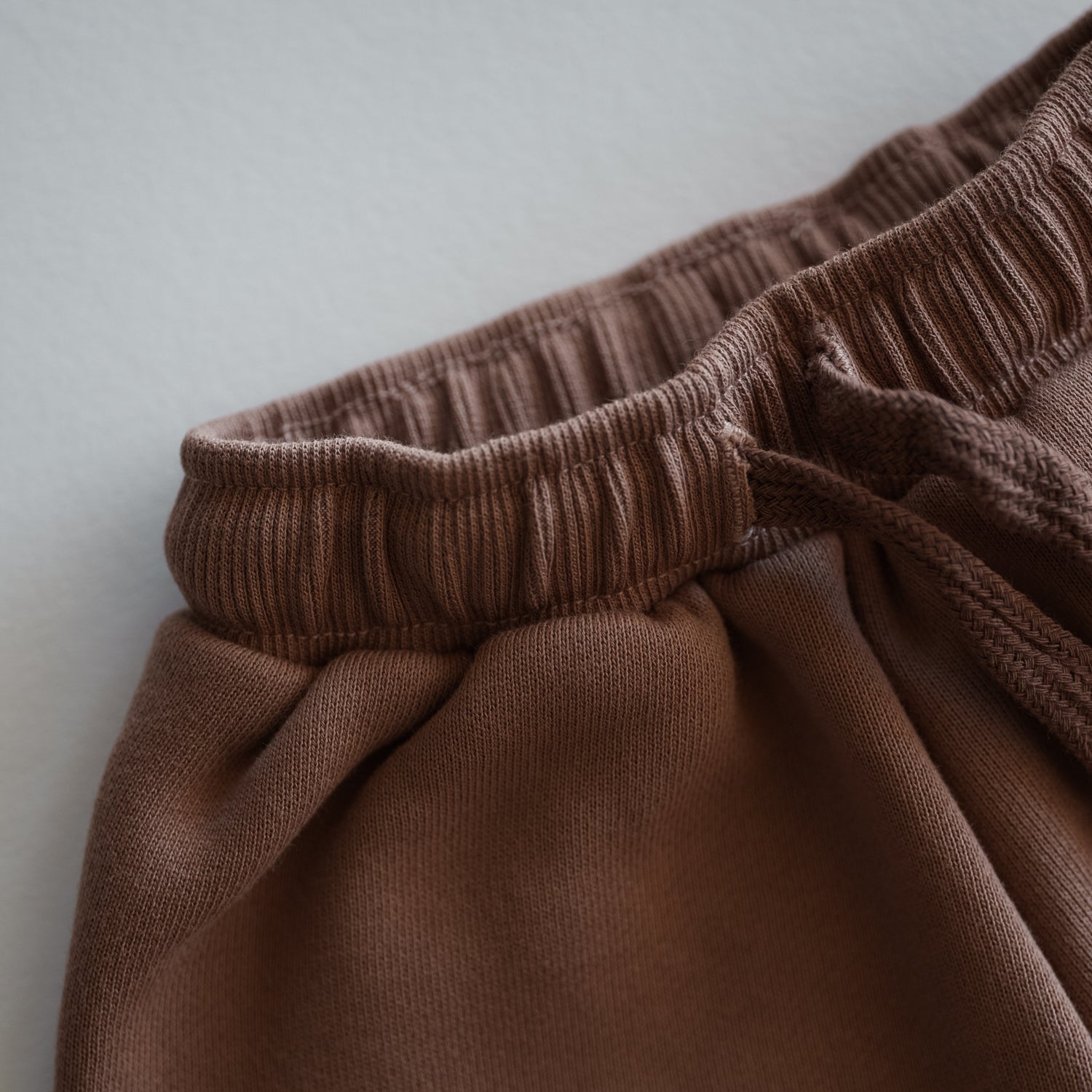 Oversized Sweatpant waistband detail in soft brown fabric for babies and kids.