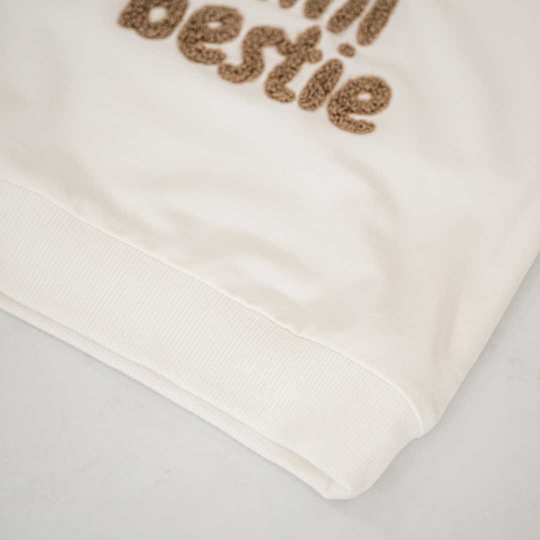 Close-up of the Mini Bestie Crewneck unisex baby sweatshirt featuring fuzzy terry-cloth embroidery.