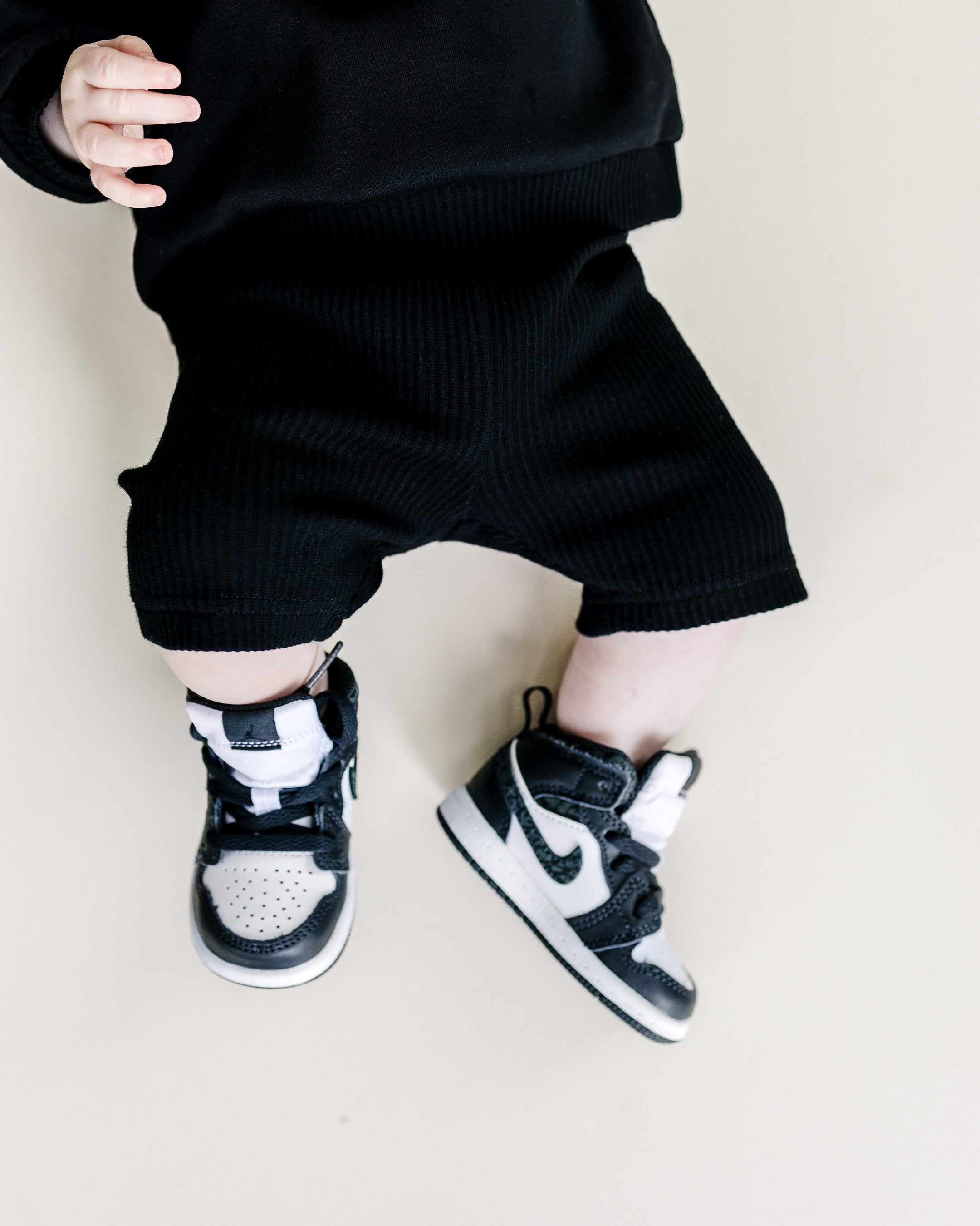 Baby in black Biker Shorts Set with stylish sneakers, showcasing a cozy and trendy lounge outfit.