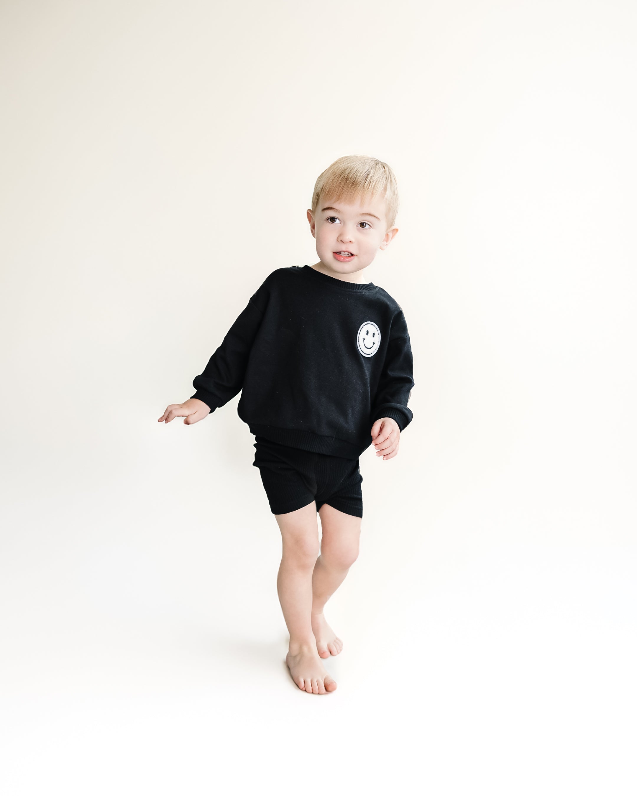 Child wearing black Biker Shorts Set, featuring a sweatshirt and shorts, perfect for casual play and comfort.