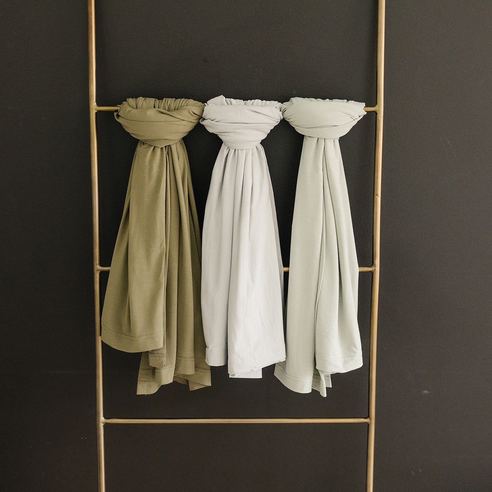 Bamboo Stretch Swaddle Sage - Baby Wraps in serene shades of sage and neutral tones hanging elegantly.