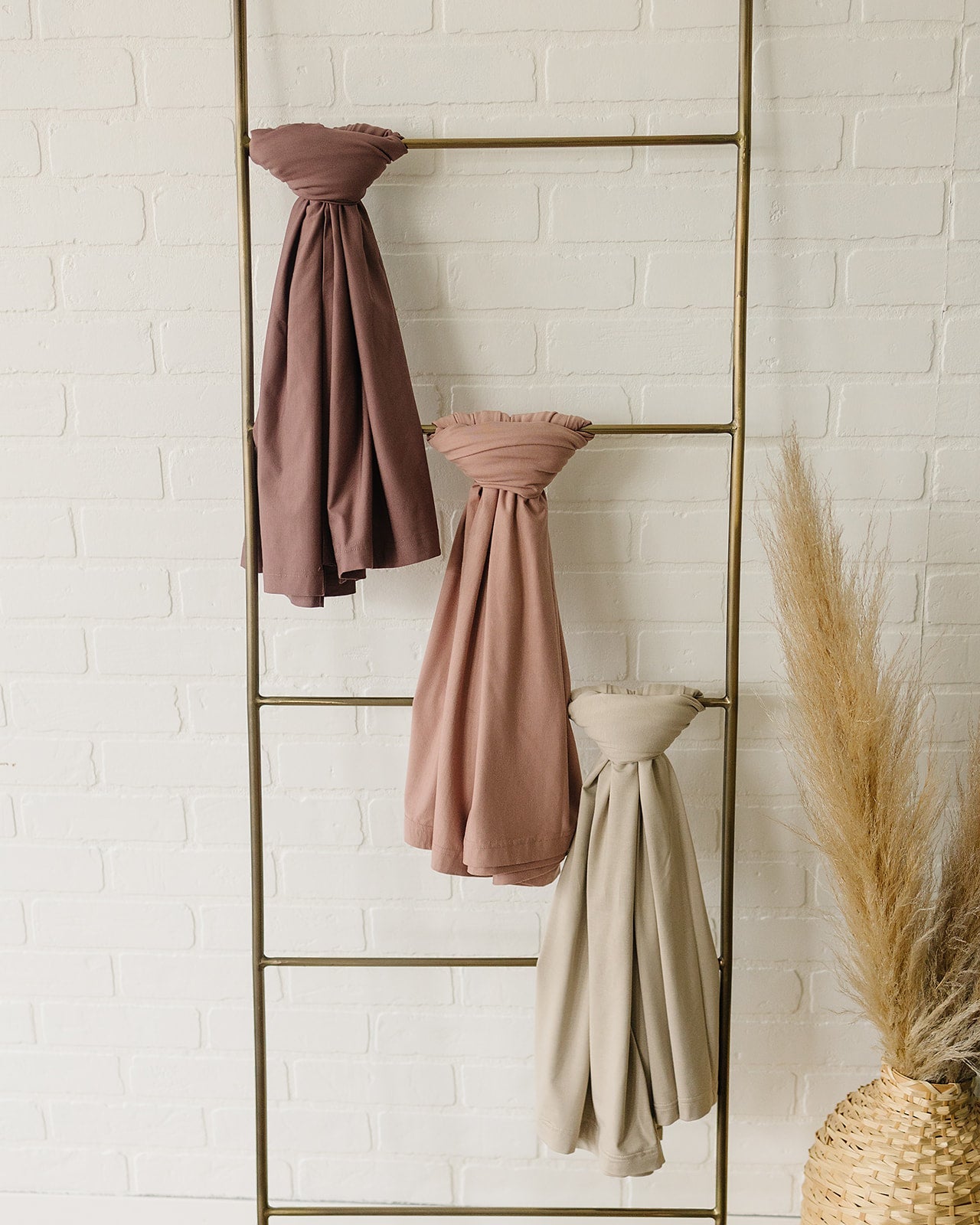 Bamboo Stretch Swaddle Oatmeal and other stylish swaddles hanging on a decorative ladder.