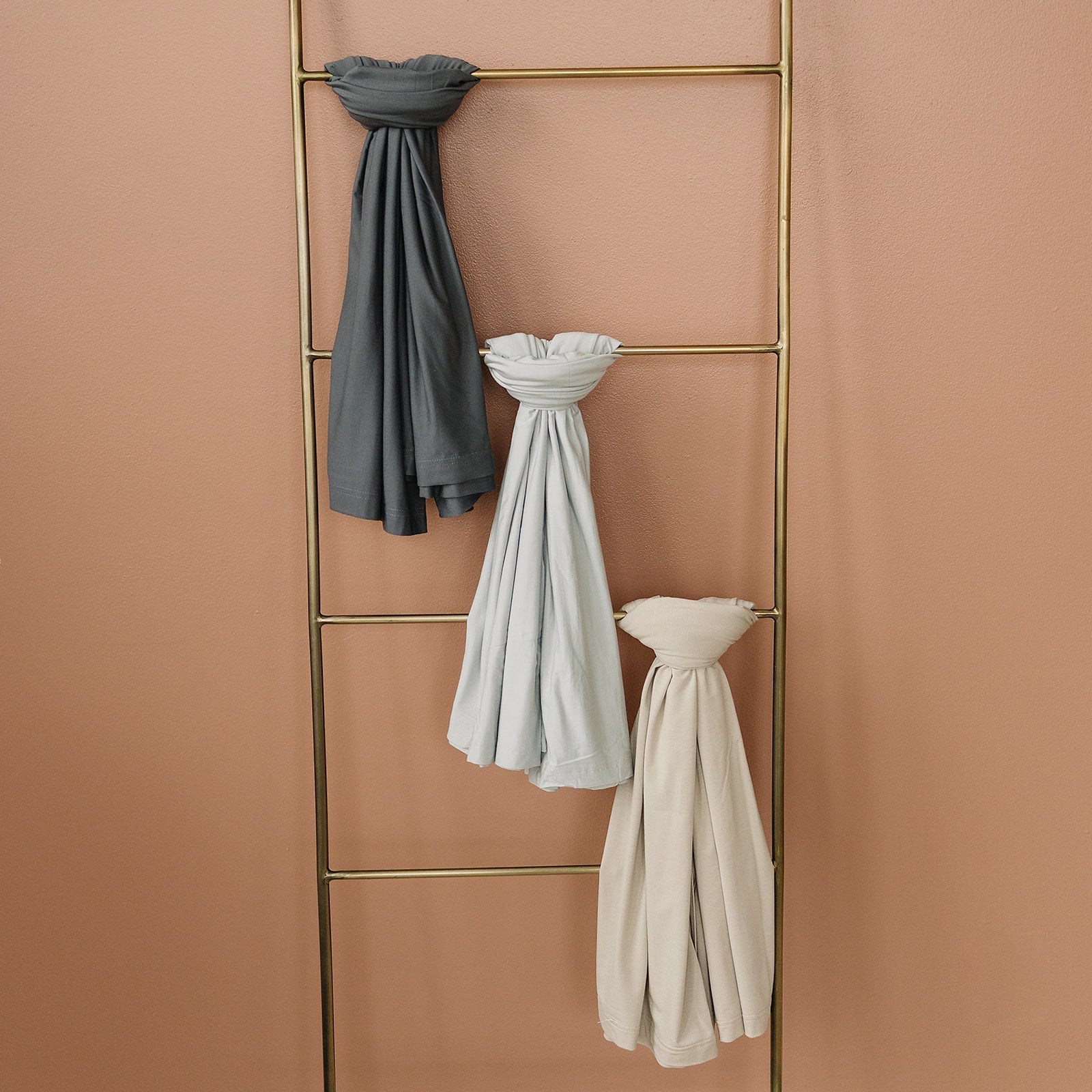 Bamboo Stretch Swaddle Oatmeal and neutral baby wraps hanging on a decorative ladder.