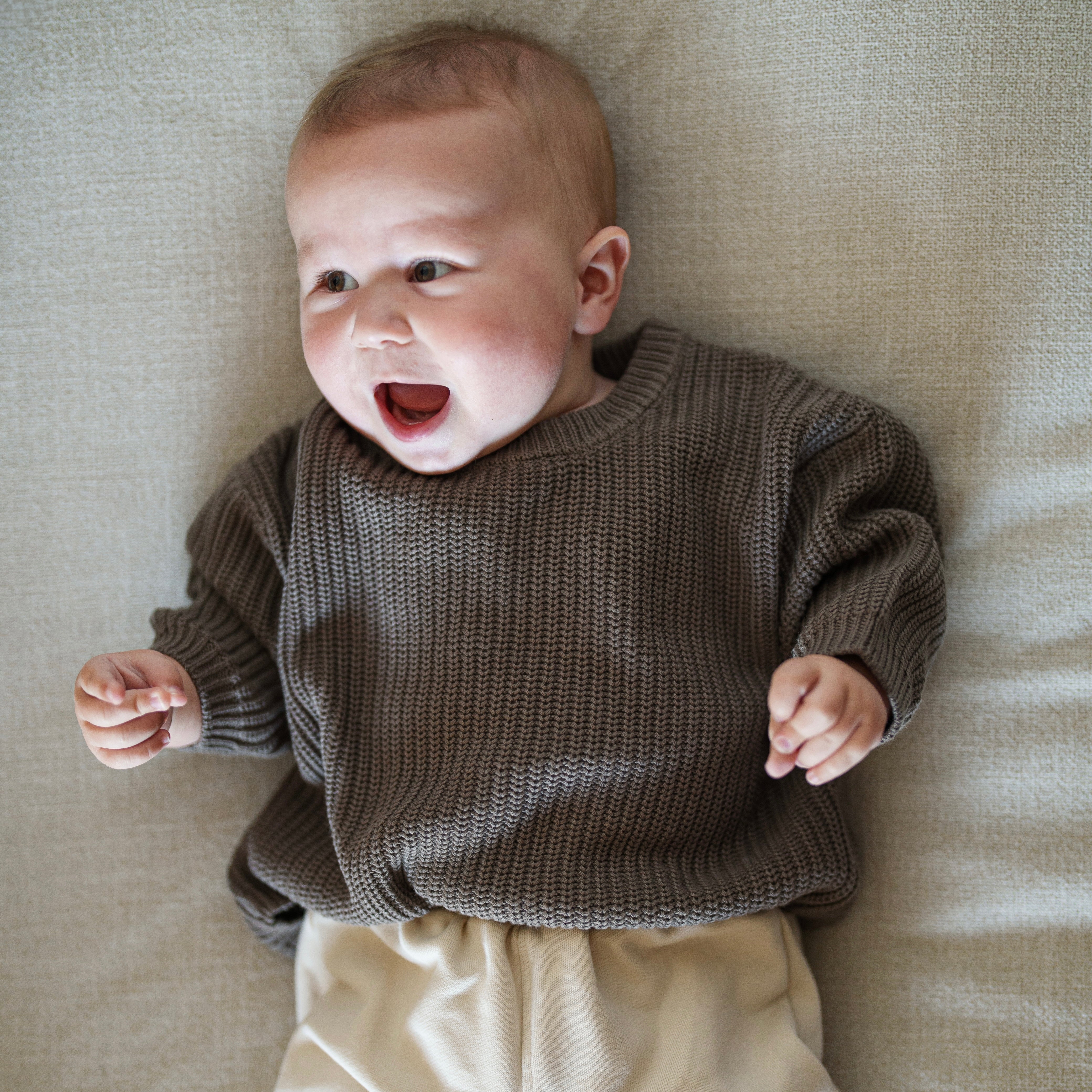Happy baby wearing Organic Chunky Knit Sweater in Coffee Bean color, showcasing comfort and style.