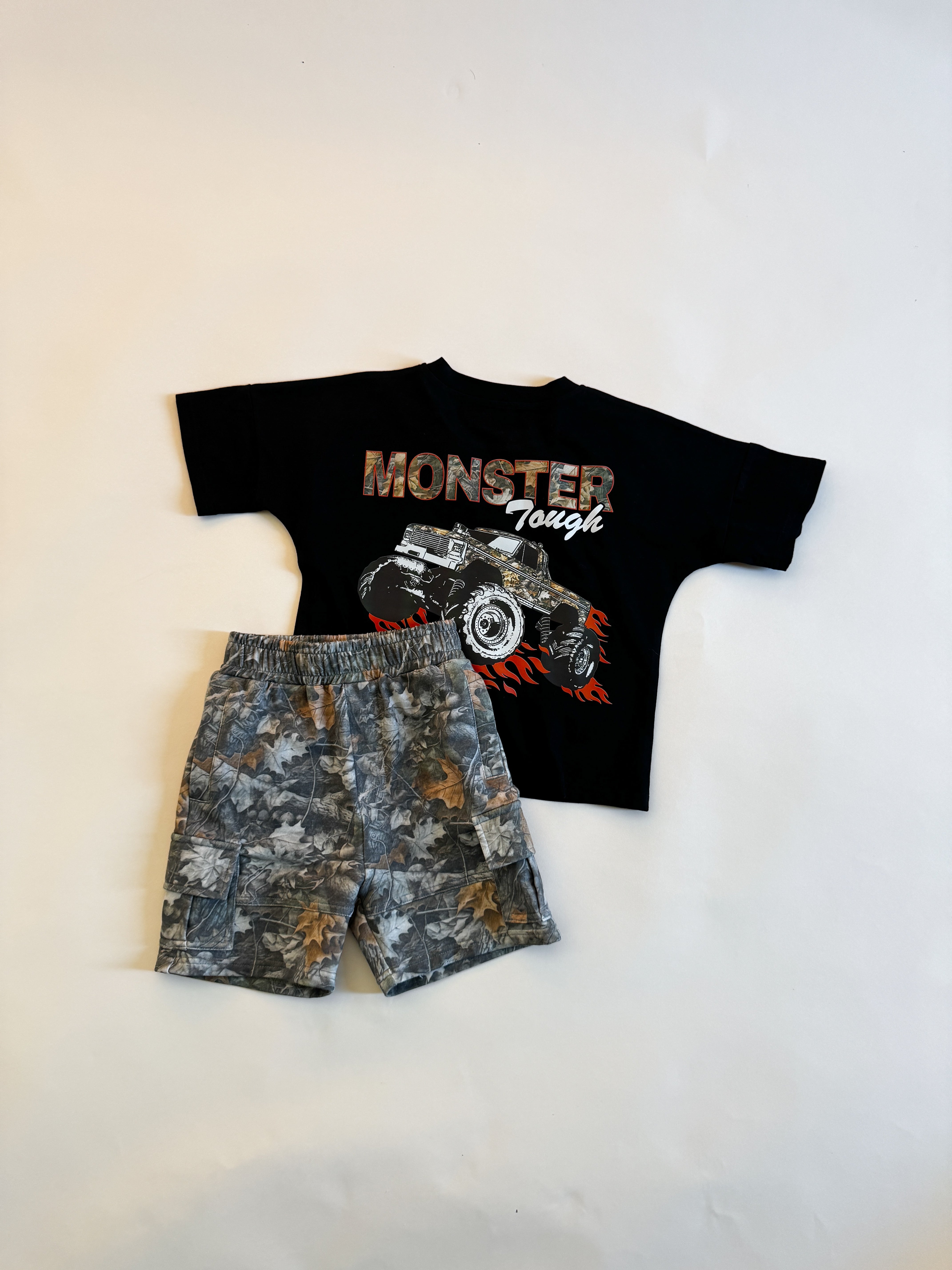 Monster truck graphic t-shirt for kids paired with camo shorts, perfect for adventurous playtime.