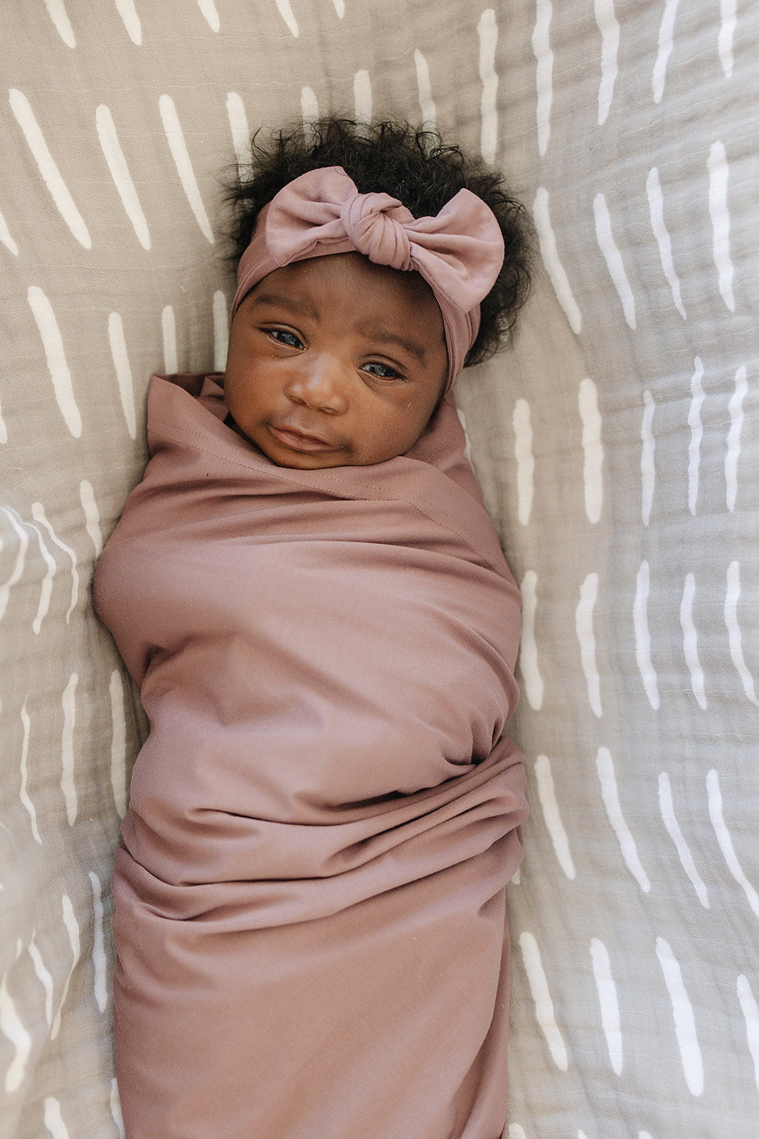 Bamboo Stretch Swaddle Dusty Rose gently wraps a baby, showcasing comfort and style in soft, breathable fabric.