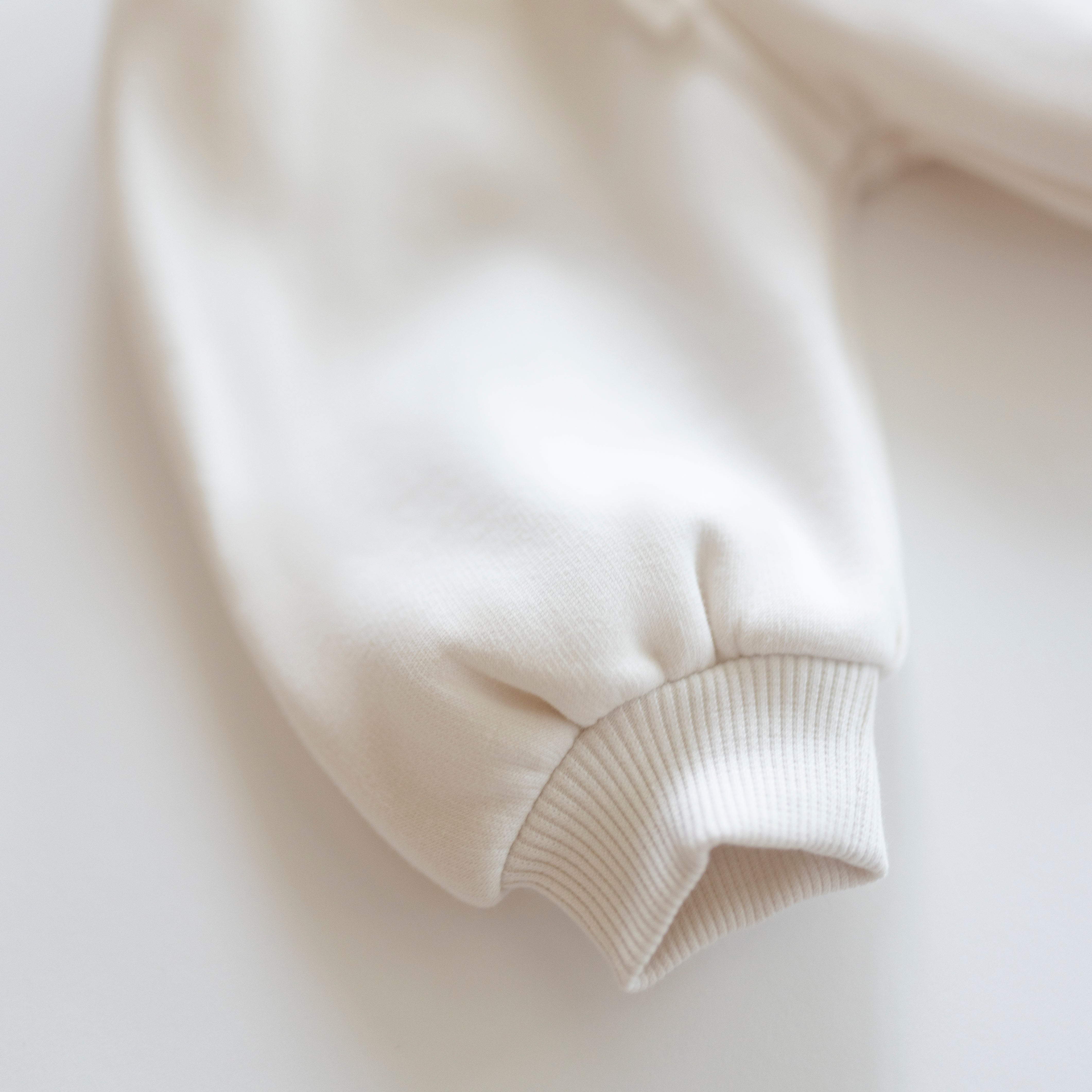 Oversized Sweatpant sleeve detail in soft white fabric, perfect for cozy comfort for babies and kids.