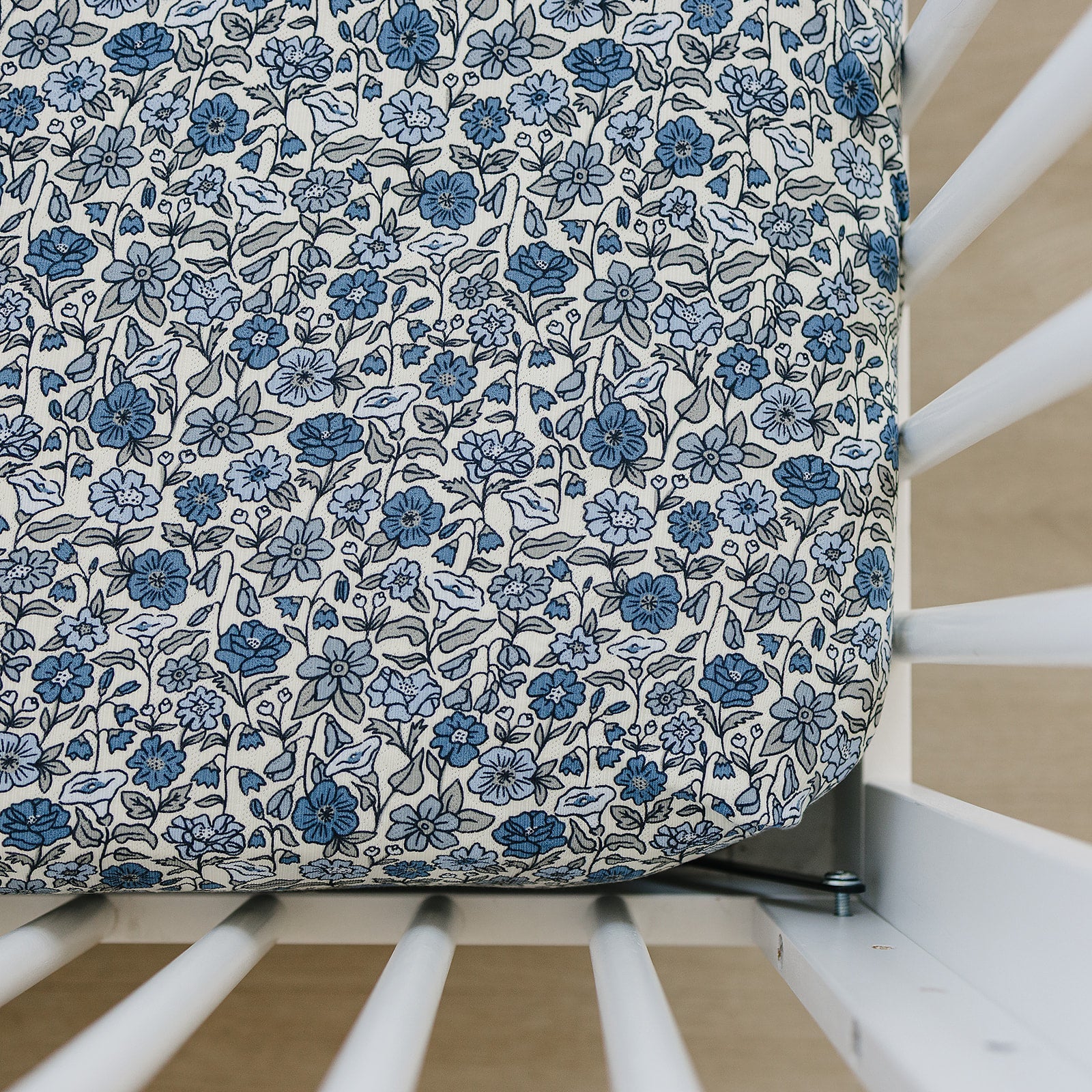 Bamboo crib sheet featuring a Bluebell Pointelle floral design in shades of blue on a crib mattress.