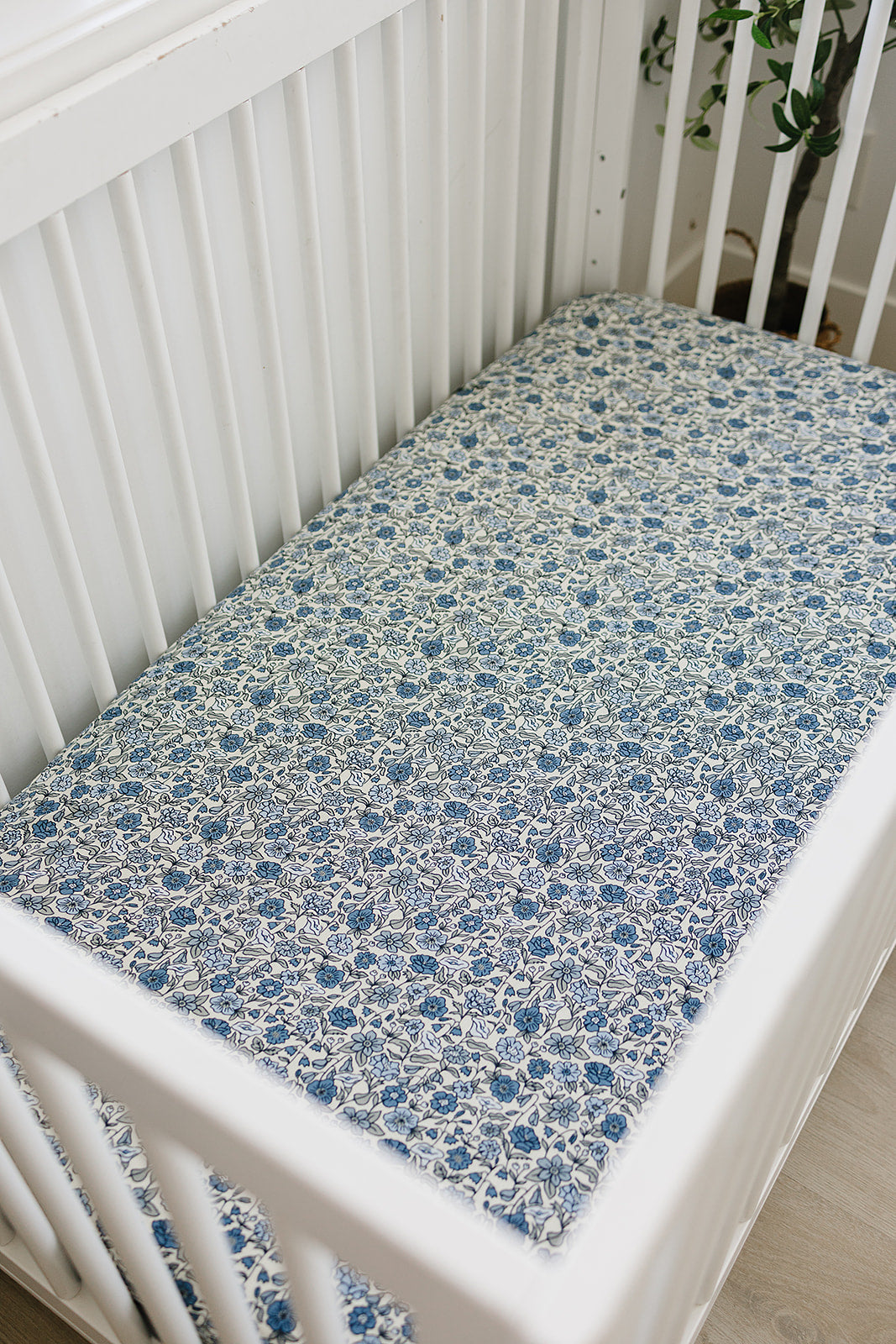 Bamboo crib sheet in Bluebell Pointelle pattern, securely fitted on a white crib for comfort and style.