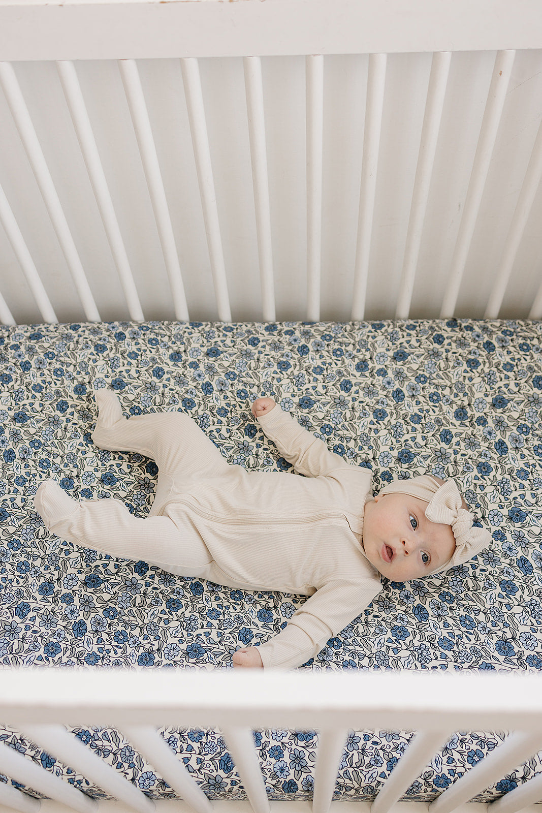 Baby laying on a Bluebell Pointelle bamboo crib sheet in a white crib, showcasing softness and comfort.