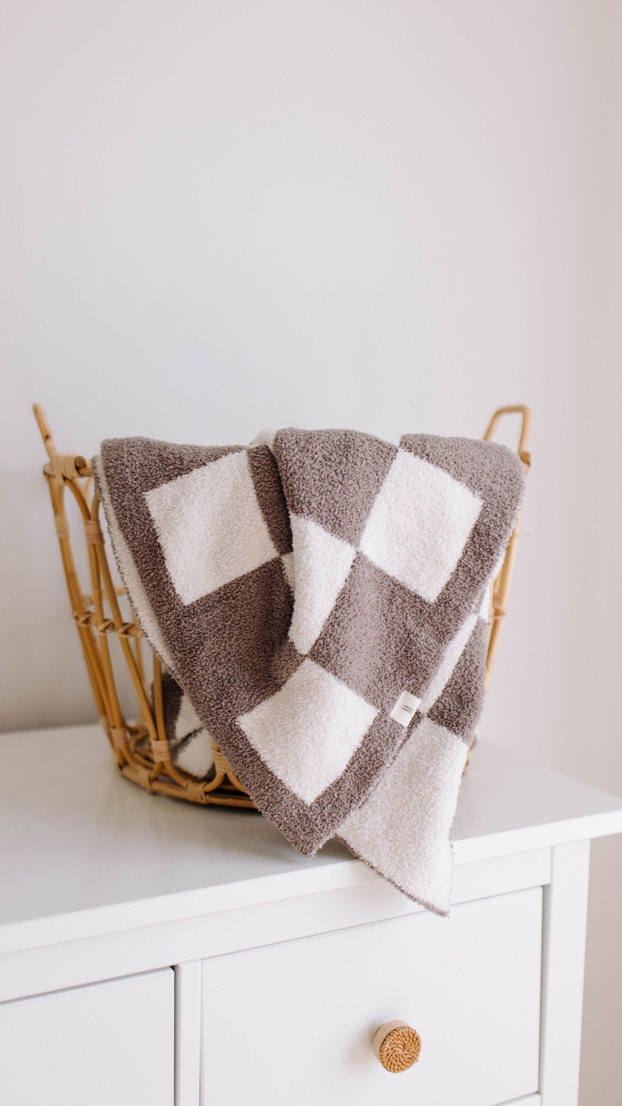 Mushroom checkerboard plush blanket draped in a basket, ideal for cozy nursery decor and toddler bedding.