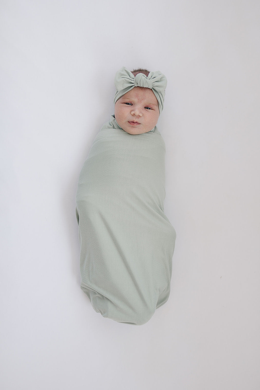 Bamboo Stretch Swaddle Sage wraps a baby in soft sage fabric for cozy comfort and style.