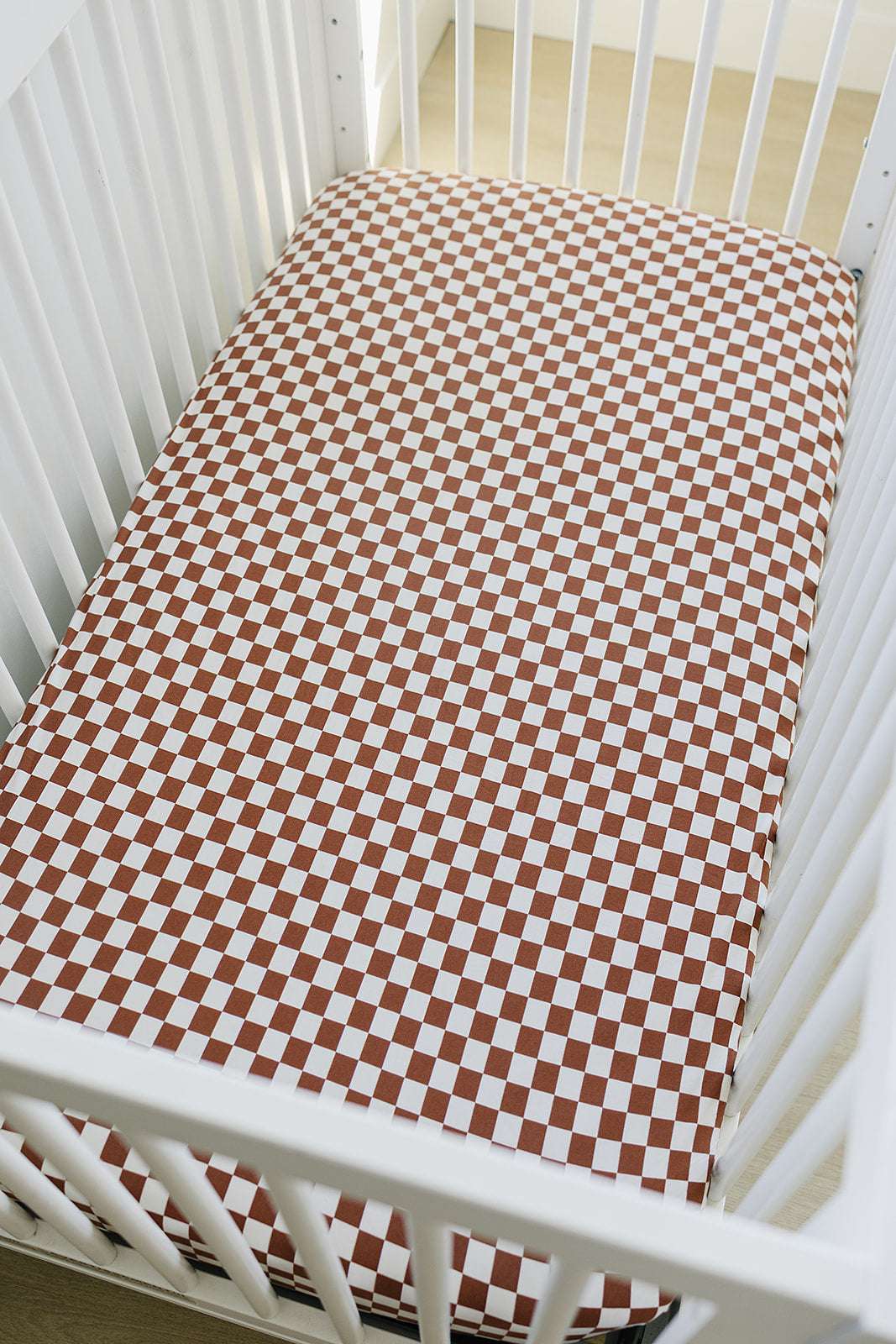 Bamboo Stretch Crib Sheet in rust checkered pattern on a white crib mattress.