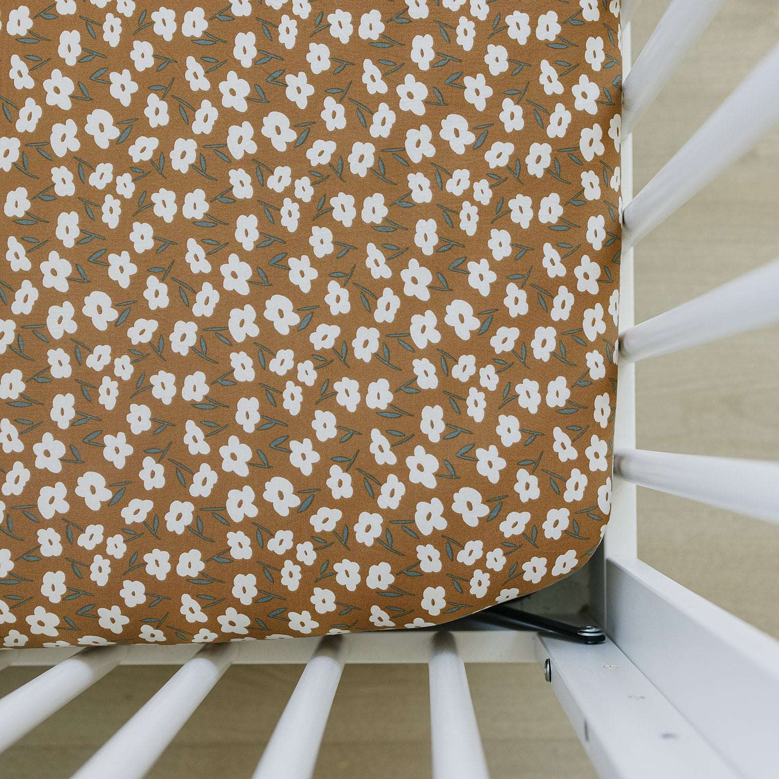 Bamboo Stretch Crib Sheet in mustard floral print on a crib mattress, adding warmth and style to the nursery.