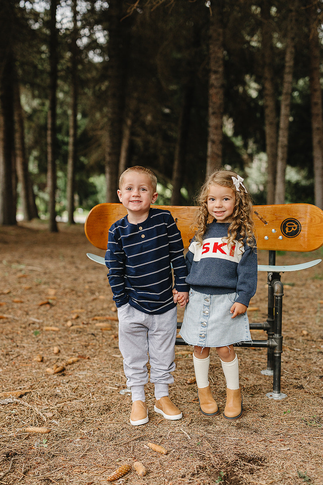 Kids long sleeve tee in navy stripes paired with stylish outfits, playing outdoors in a forest setting.
