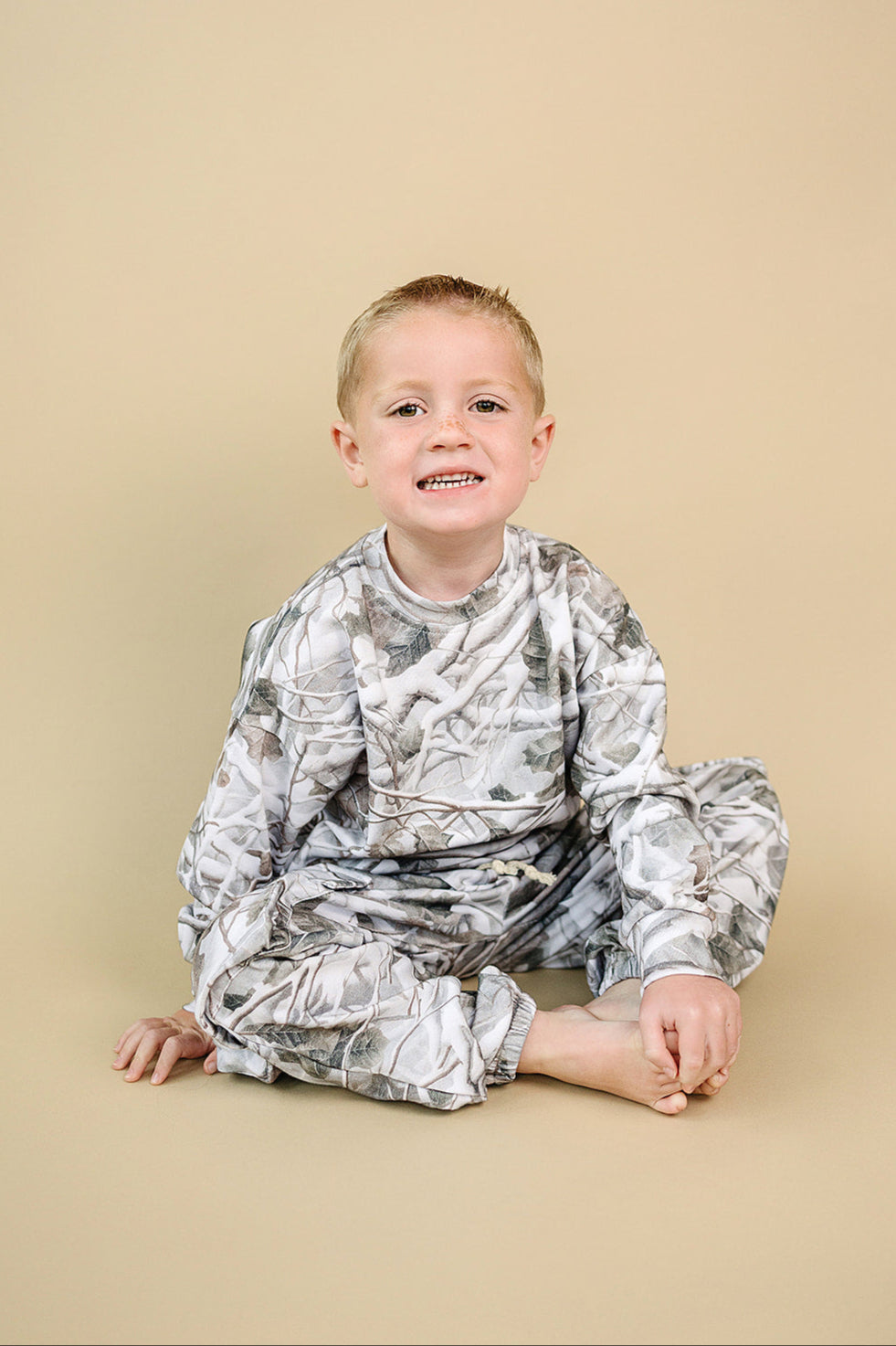 Camo kids lounge set featuring a smiling boy in camo outfit, perfect for play and relaxation.