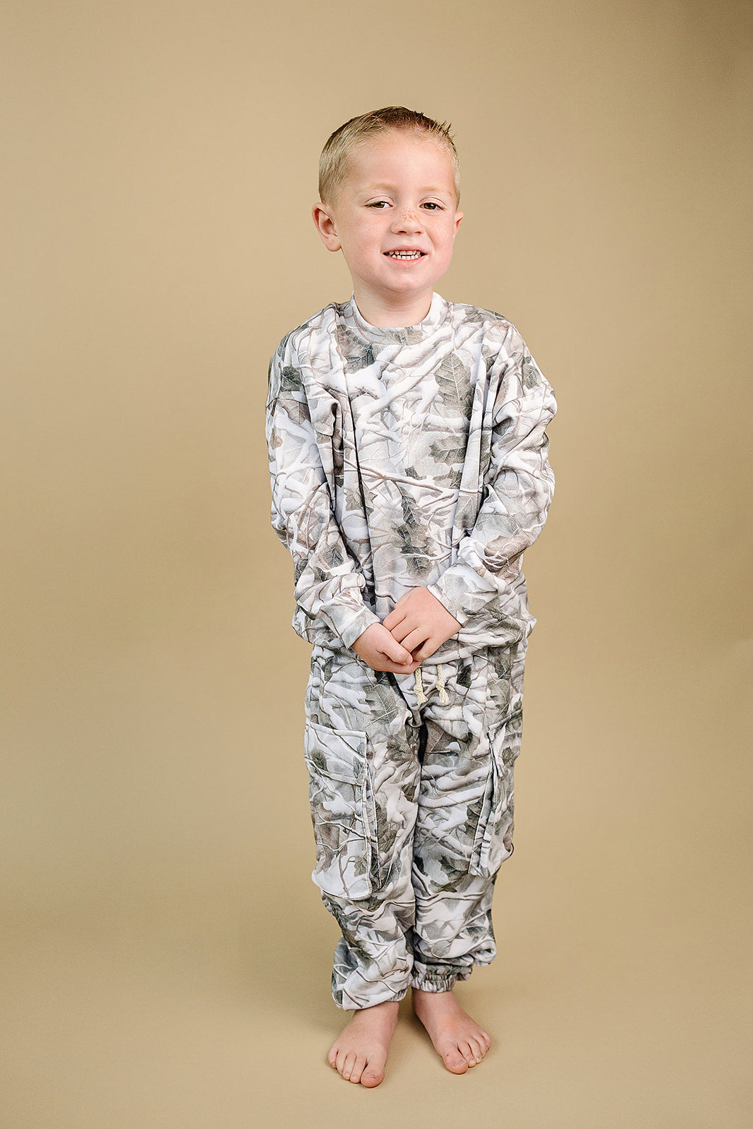 Camo kids lounge set featuring a young boy wearing a pullover hoodie and cargo joggers in classic camo print.