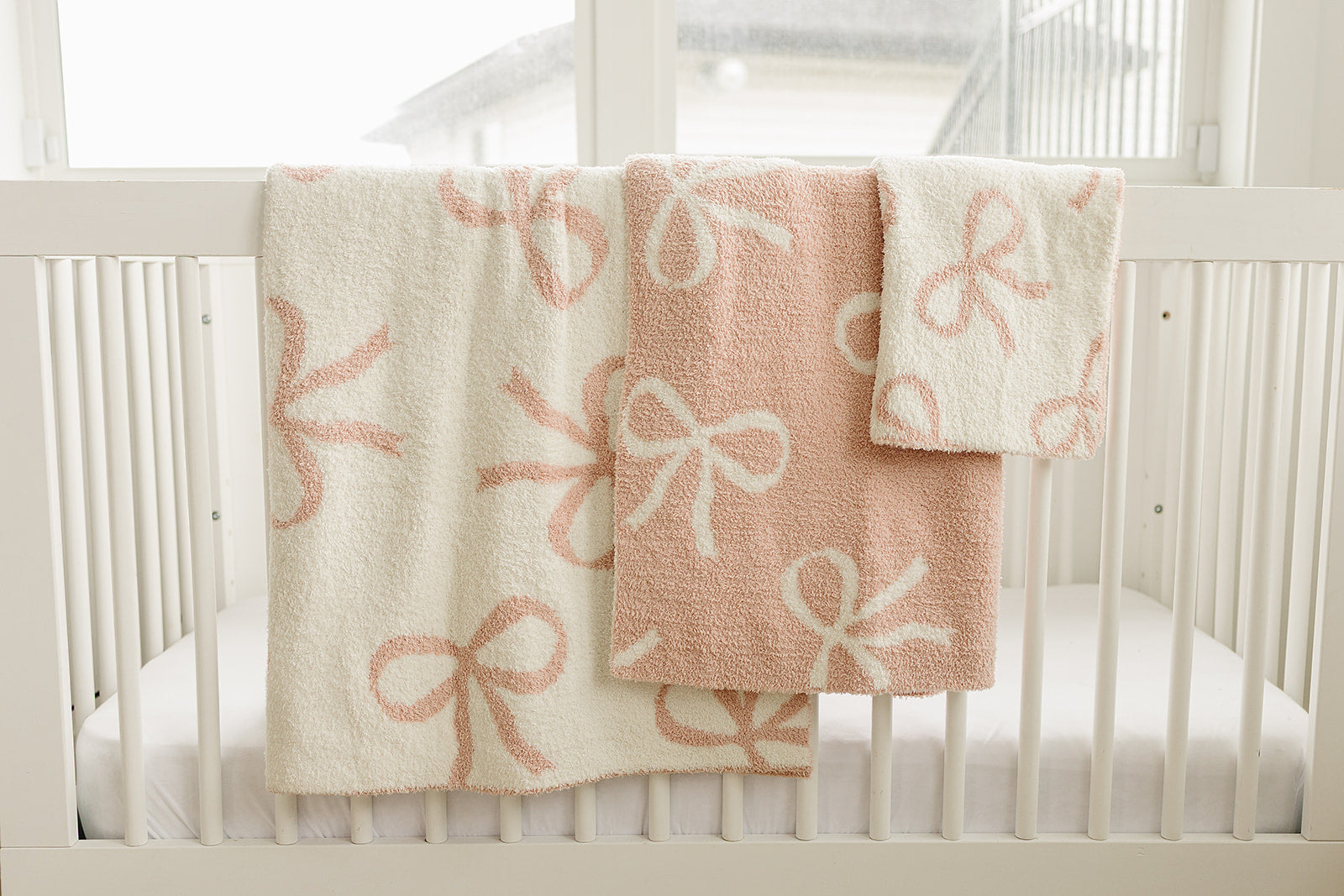 Pink Bow Plush Blanket in cute pink bow designs displayed on a crib, perfect for nursery decor.