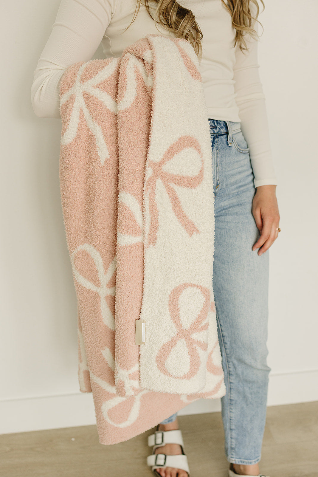 Woman holding a Pink Bow Plush Blanket featuring a soft minky fabric and charming pink bow design.