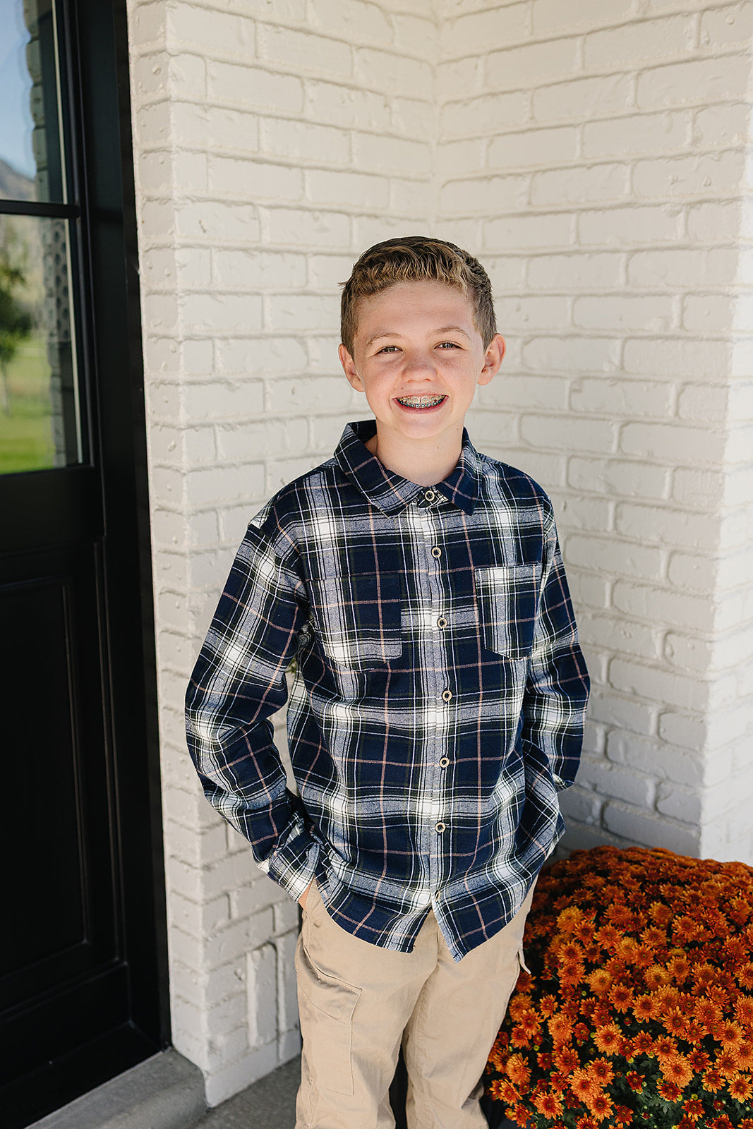 Smiling boy wearing a navy plaid button-up shirt for babies & kids, showcasing a classic style and comfort.