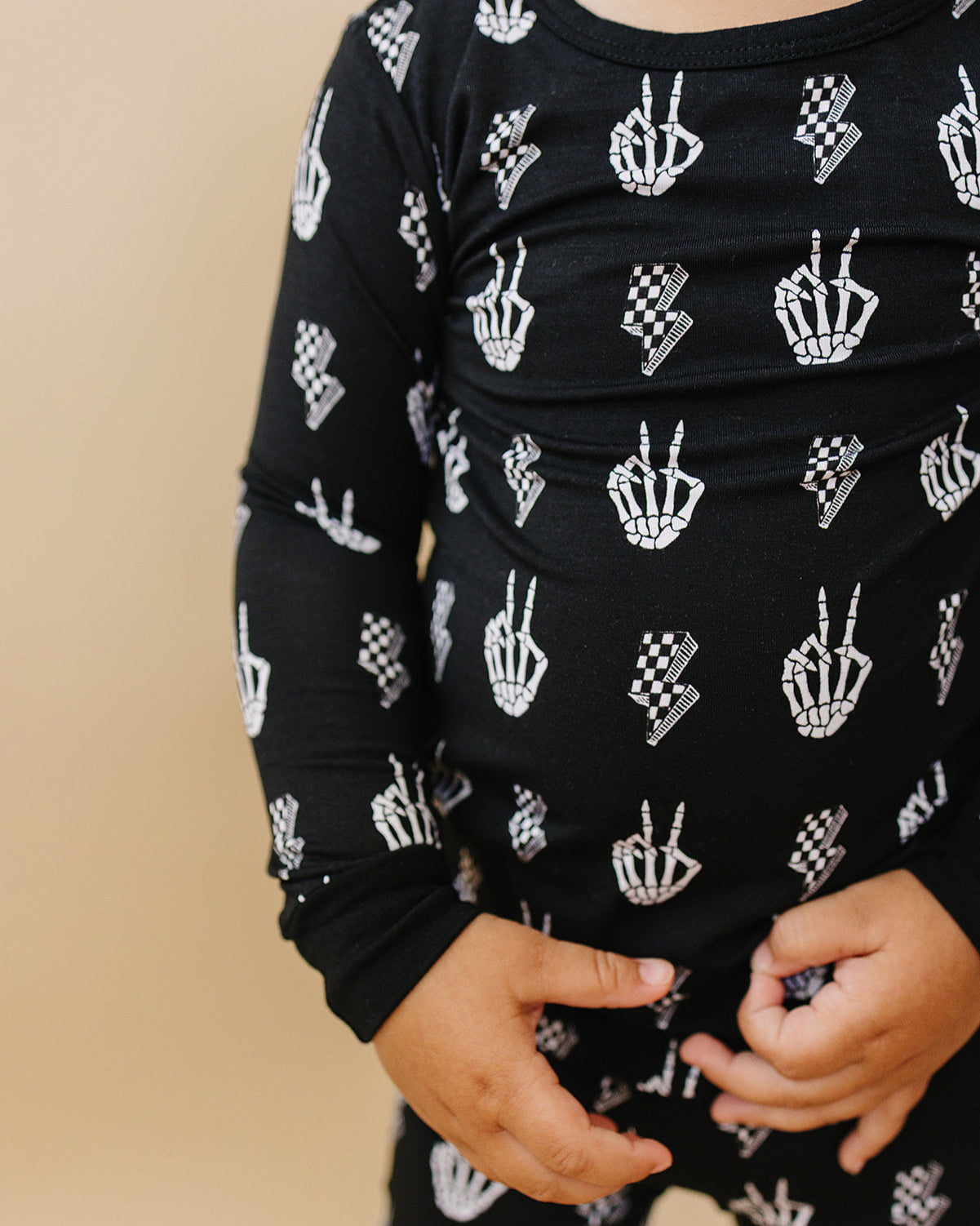 Child wearing Bamboo Two-Piece Set Skelly Vibes with playful skeleton graphics on a black background.