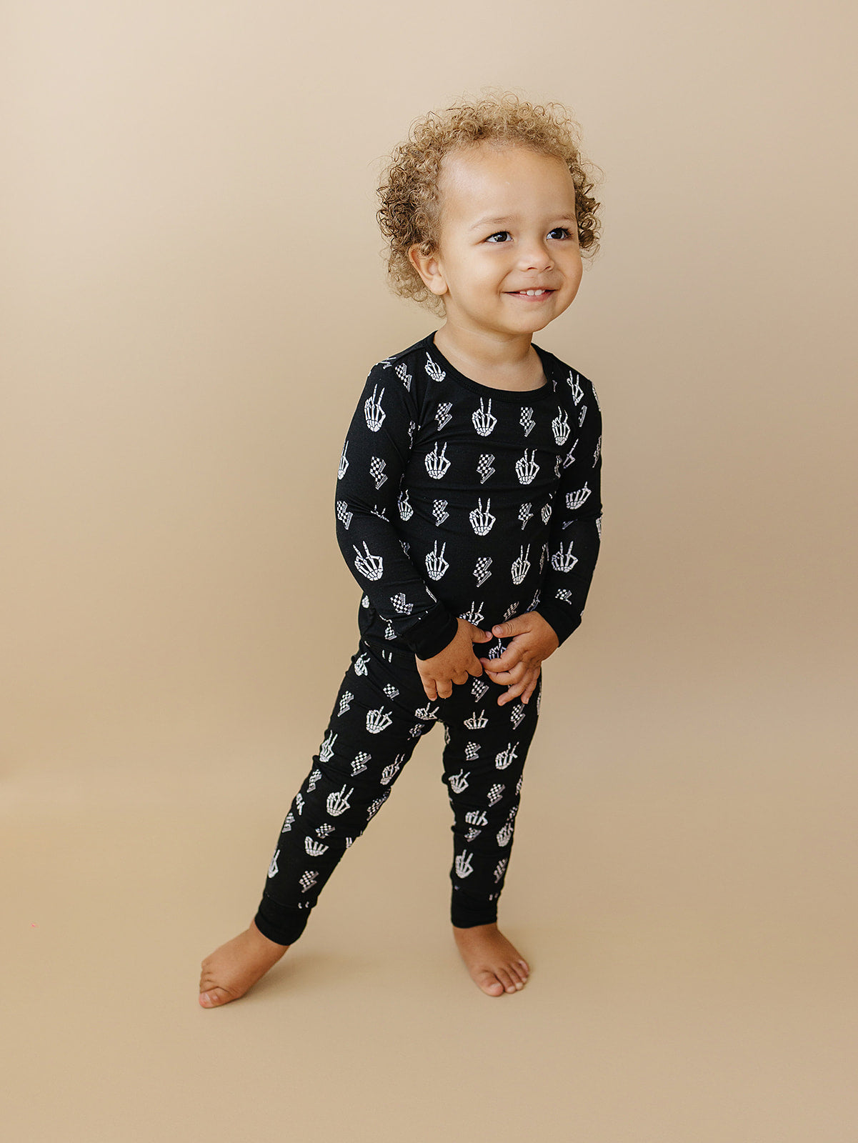 Happy child wearing Bamboo Two-Piece Set Skelly Vibes with playful skeleton graphics, perfect for lounging.