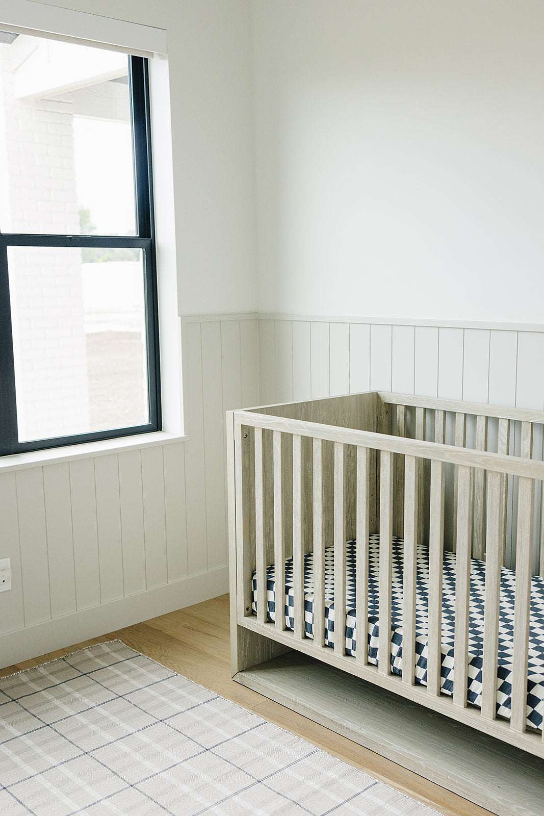 Muslin Crib Sheet in a modern nursery with charcoal checkered pattern fitting snugly on crib mattress.