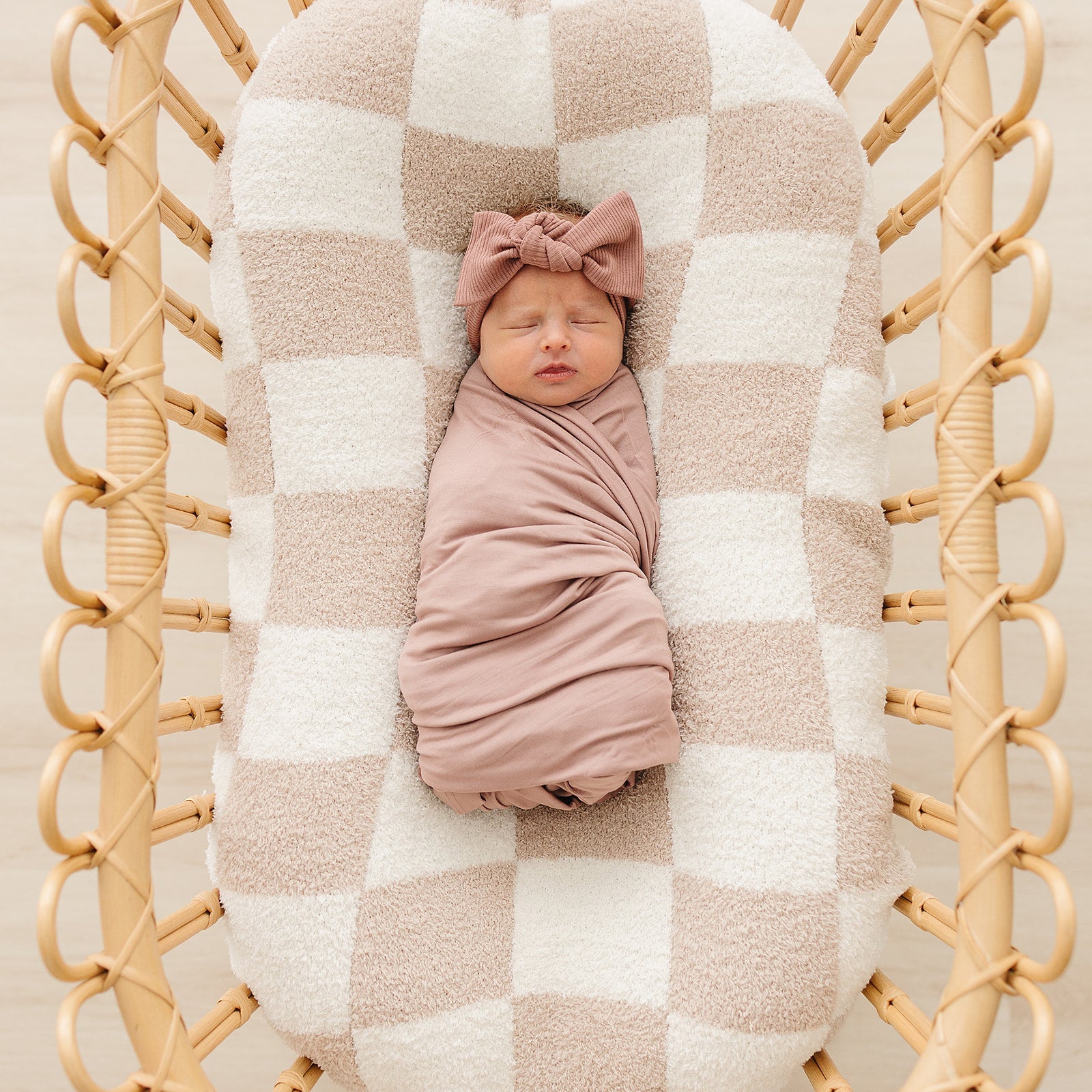Bamboo Stretch Swaddle Dusty Rose used for a newborn, gently wrapped in a cozy bassinet.