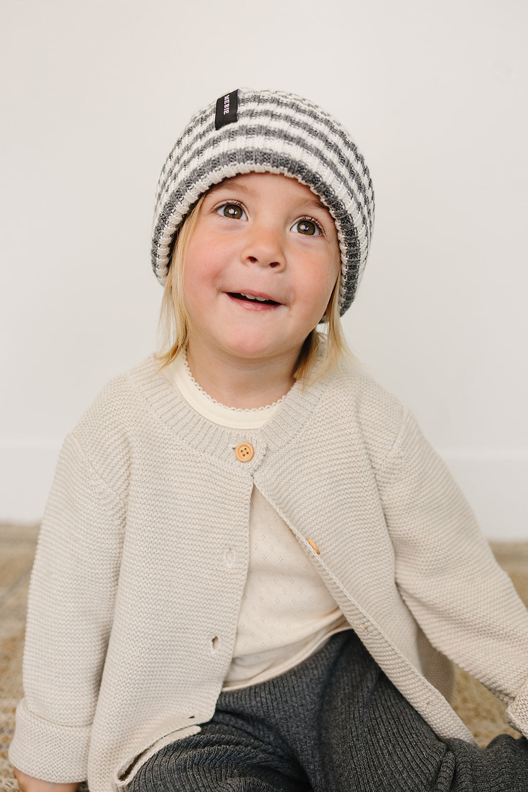 Happy child wearing a grey and white baby beanie, featuring a chunky knit design, in a cozy outfit.