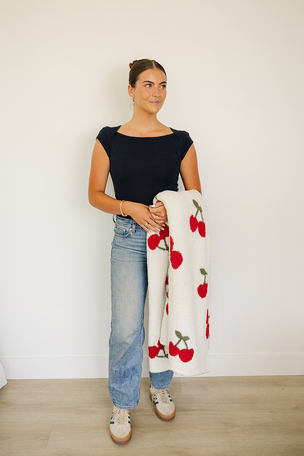 A girl holding a Cherry Baby Plush Blanket featuring a playful cherry print, perfect for nurseries.