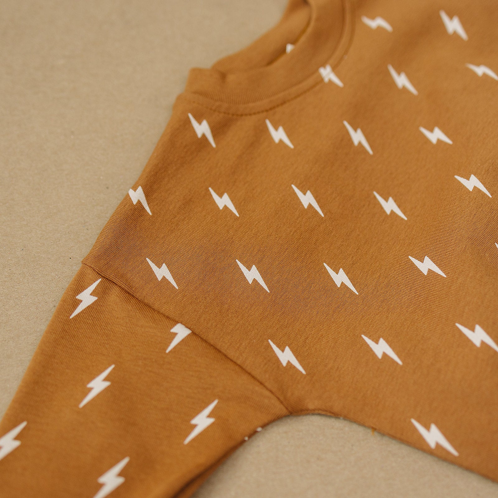 Close-up of the Fall Bolts Kids Lounge Set showcasing lightning bolt print on a cozy brown fabric.