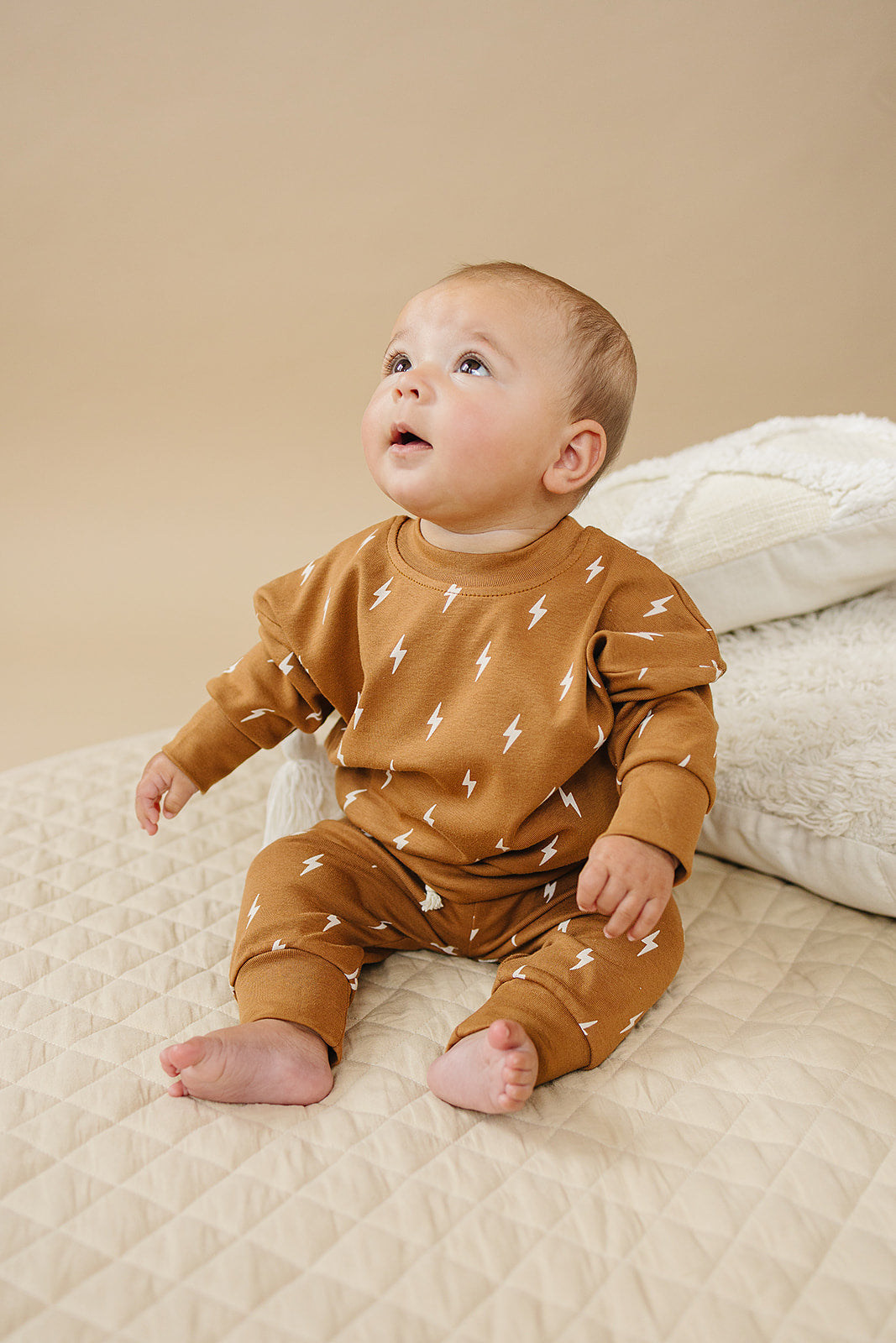 Fall Bolts Kids Lounge Set featuring a baby in a lightning bolt print outfit sitting on a cozy textured blanket.