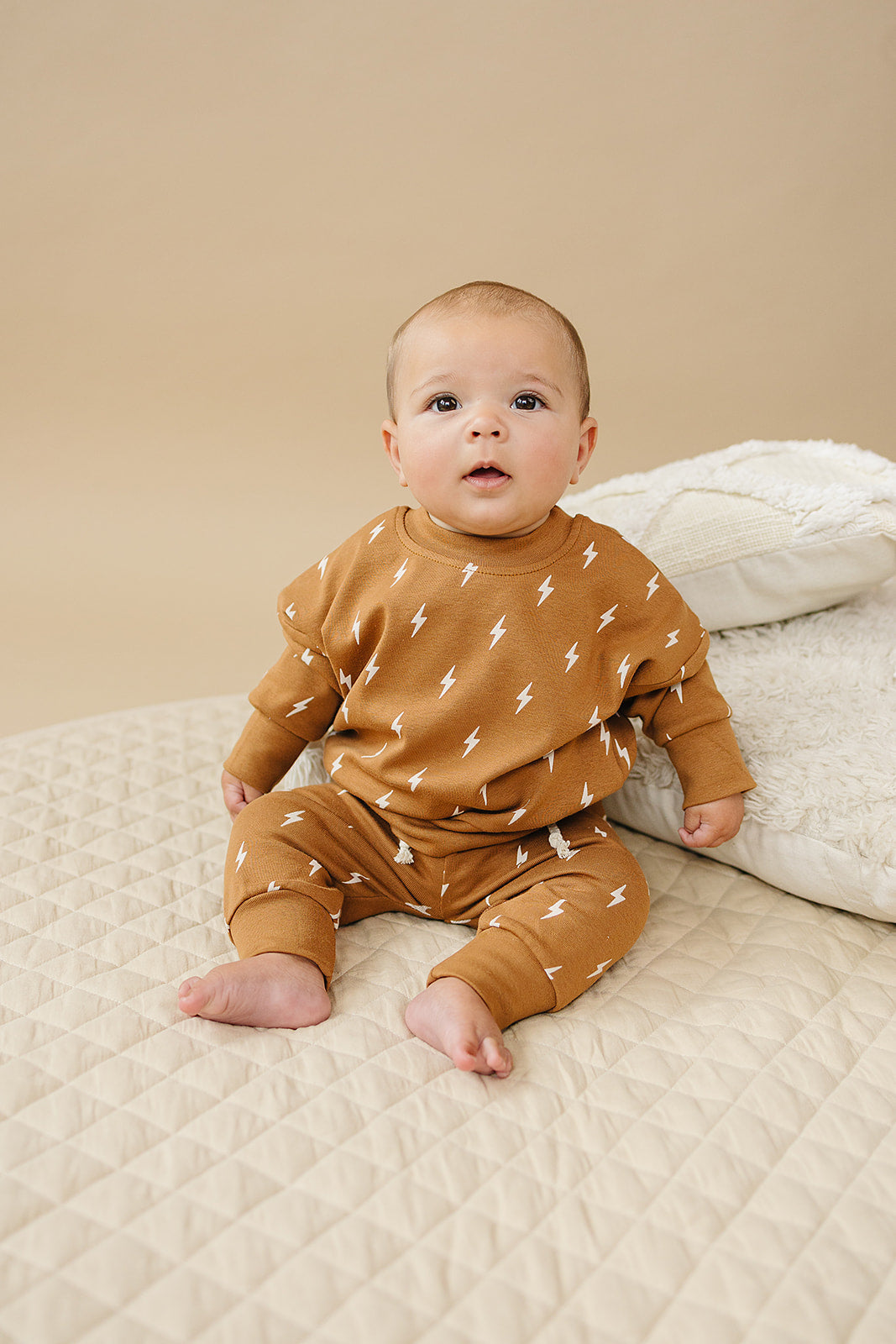Fall Bolts Kids Lounge Set - Baby in comfy pullover and joggers with lightning bolt print on a beige background.