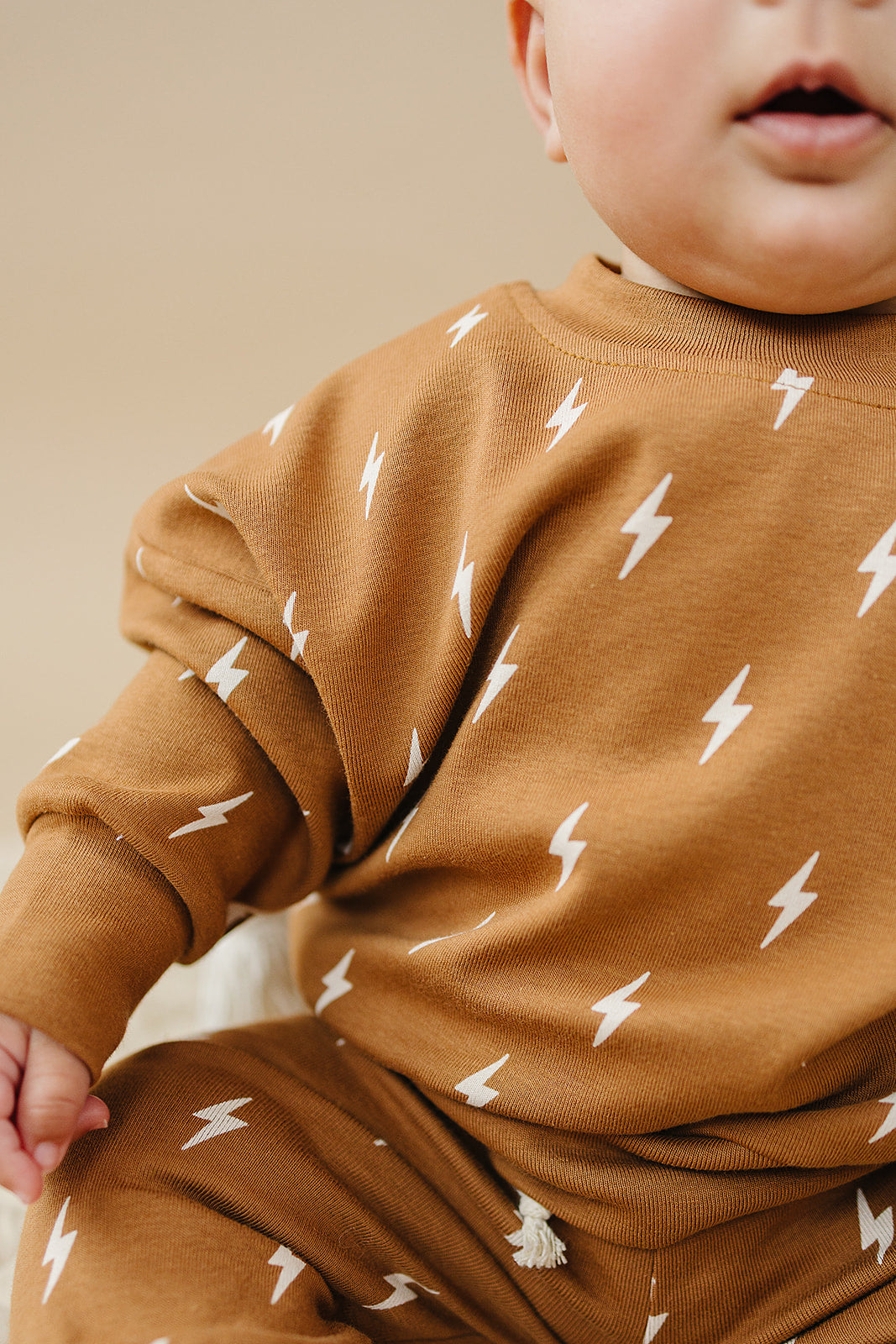 Fall Bolts Kids Lounge Set featuring a baby wearing a brown pullover with lightning bolt print.
