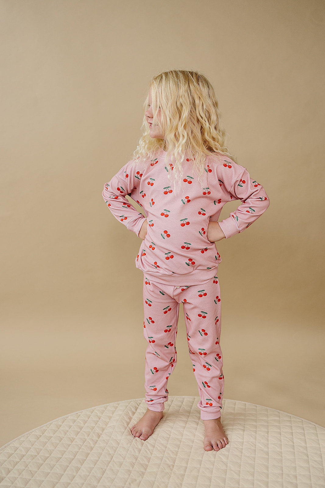 Blush Cherry Kids Lounge Set worn by a child, featuring a playful cherry print on a relaxed-fit pink outfit.