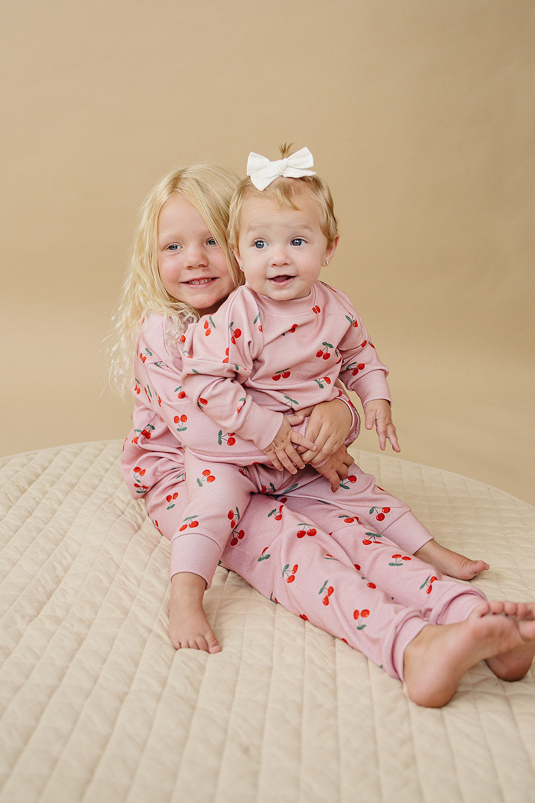 Blush Cherry Kids Lounge Set worn by two smiling girls, showcasing playful cherry print on comfy lounge outfits.