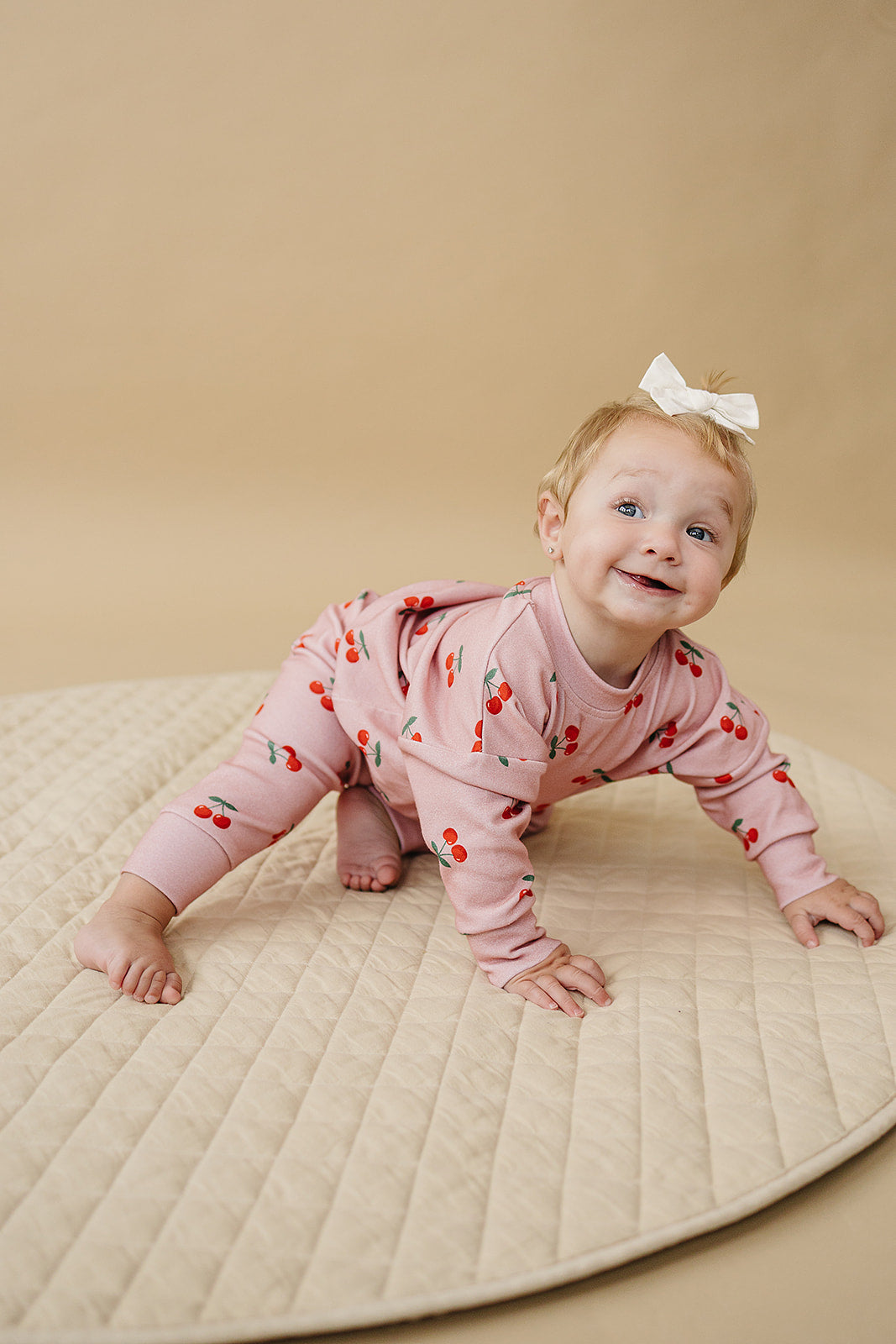Adorable baby wearing Blush Cherry Kids Lounge Set crawling on a soft mat, showcasing a cute cherry print.