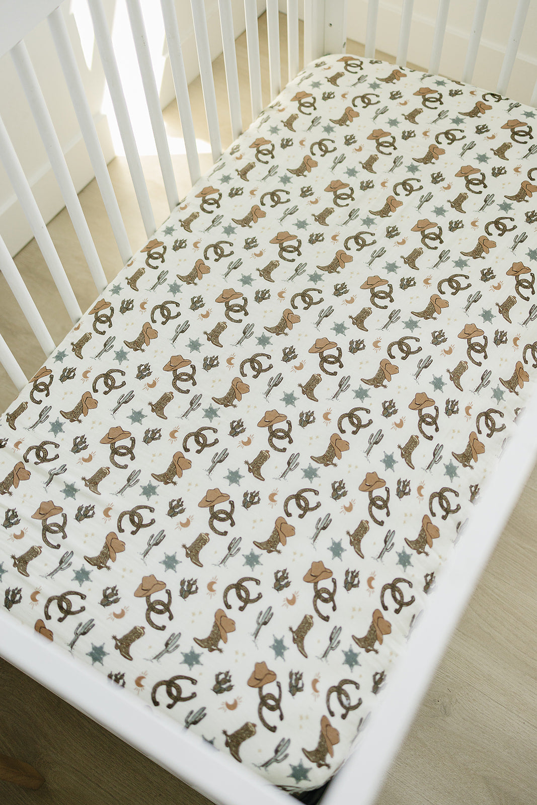 Muslin crib sheet featuring a playful outlaw cowboy design, perfect for adding a western touch to a nursery.