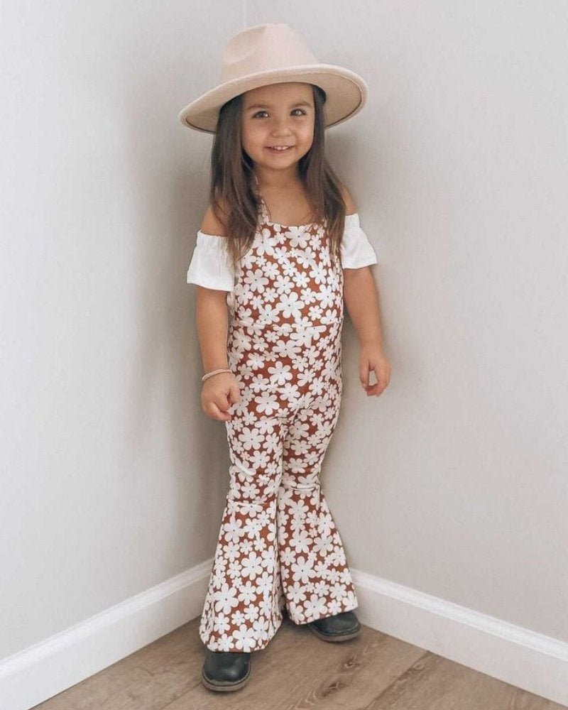 Little girl in Andi pleated bell bottom jumpsuit with floral print and hat, perfect for flower children.