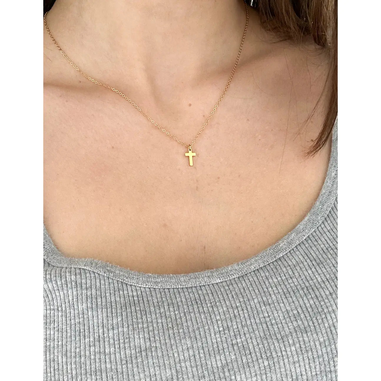 Gold cross necklace for women worn on a delicate chain, perfect for everyday wear or special occasions.