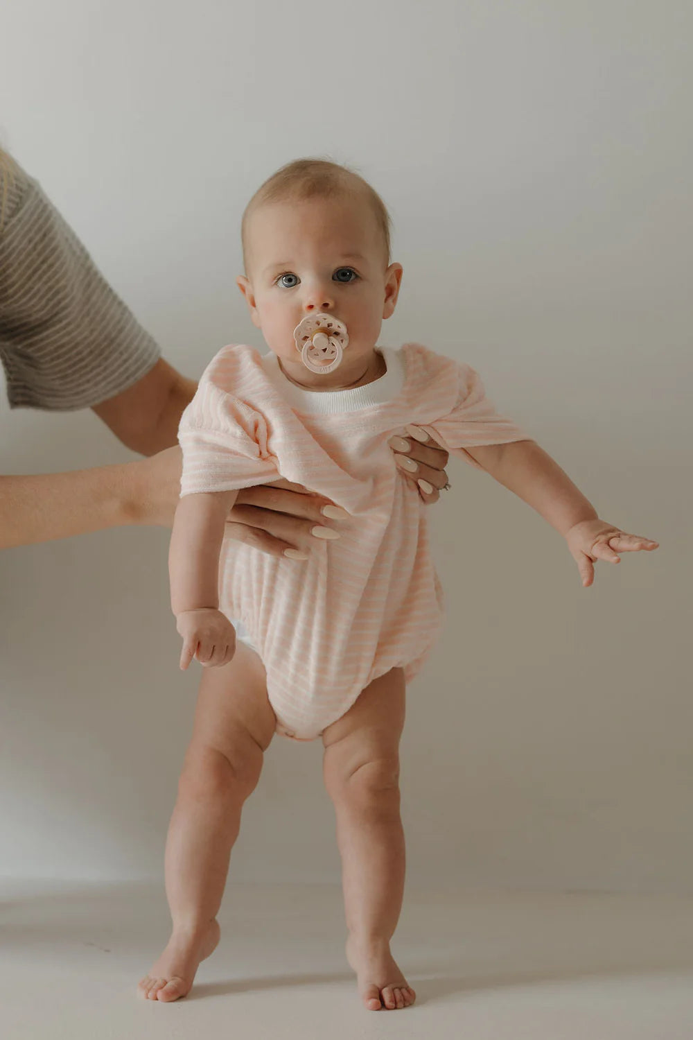 Baby wearing pink striped romper from mom-owned ethical kids clothing brand
